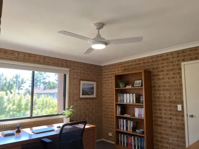 Ceiling fan with light in a brick-walled home office with desk, bookshelf and window in Glenhaven
