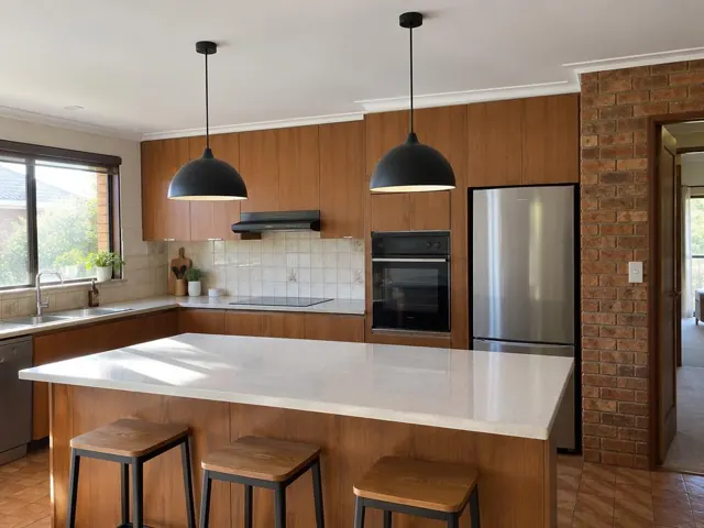 Two black pendant lights over a kitchen island in a modern kitchen with timber cabinets in Glenhaven
